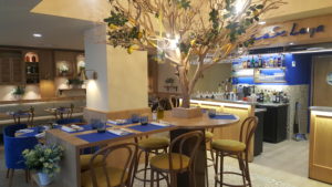 Image représentant la salle du rez-de-chaussée décorée comme le reste du restaurant en jaune et bleu, avec des produits italiens. Il y a également le citronnier de l'entrée du restaurant. Il donne une ambiance chaleureuse et typique italienne.